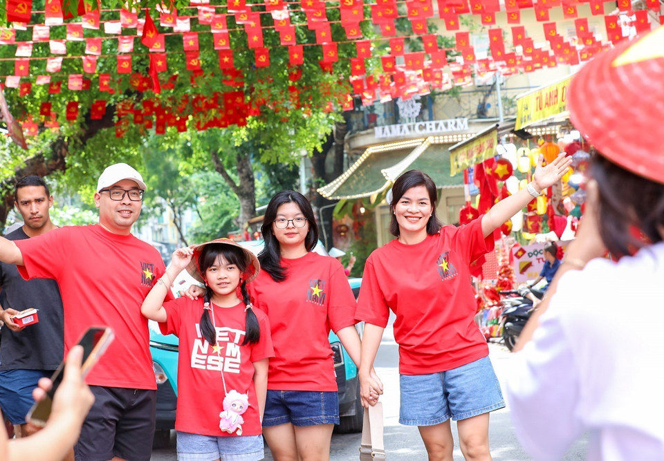 Residents capture moments with national flags on Hang Ma Street, Hoan Kiem District. (Photo: VNA)
