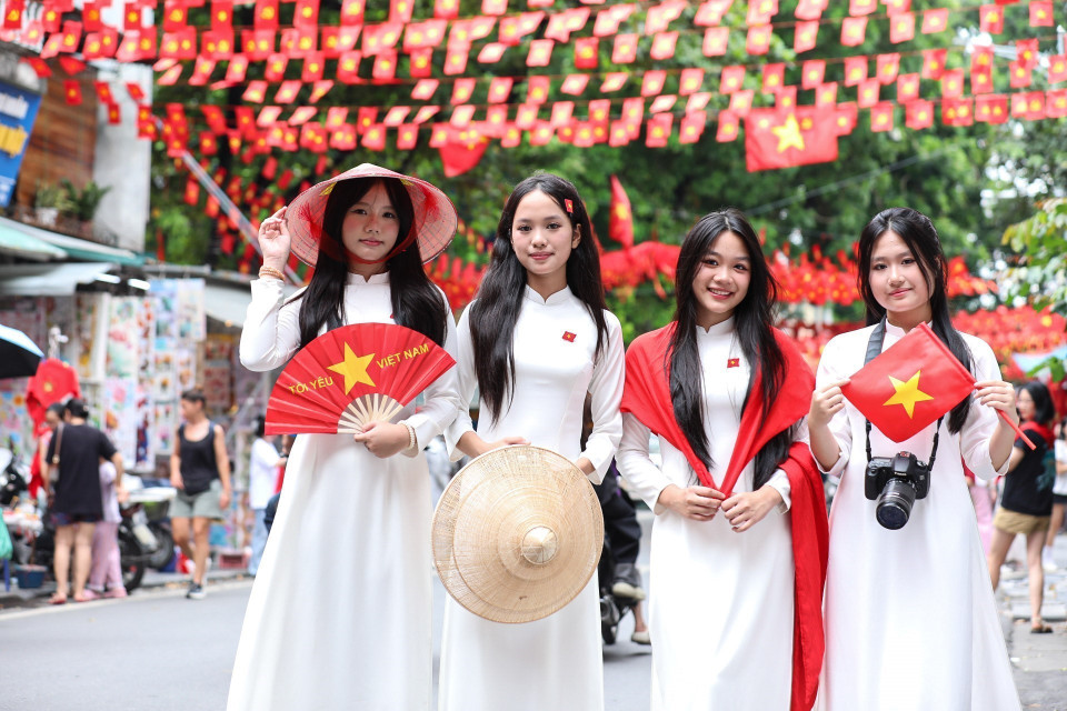 Young people pose with national flags on Hang Ma Street, Hoan Kiem District. (Photo: VNA)