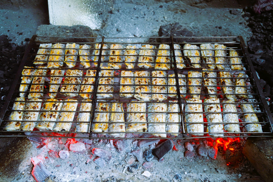 Hairtail fish, with fins removed and cut into sections, are grilled over charcoal fires. (Photo: VNA)