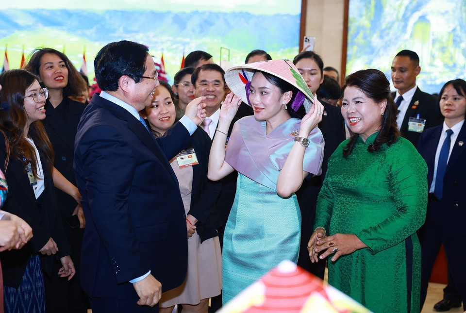 Prime Minister Pham Minh Chinh places a conical hat from Chuong Village on Prime Minister Paetongtarn Shinawatra's head. (Photo: VNA)