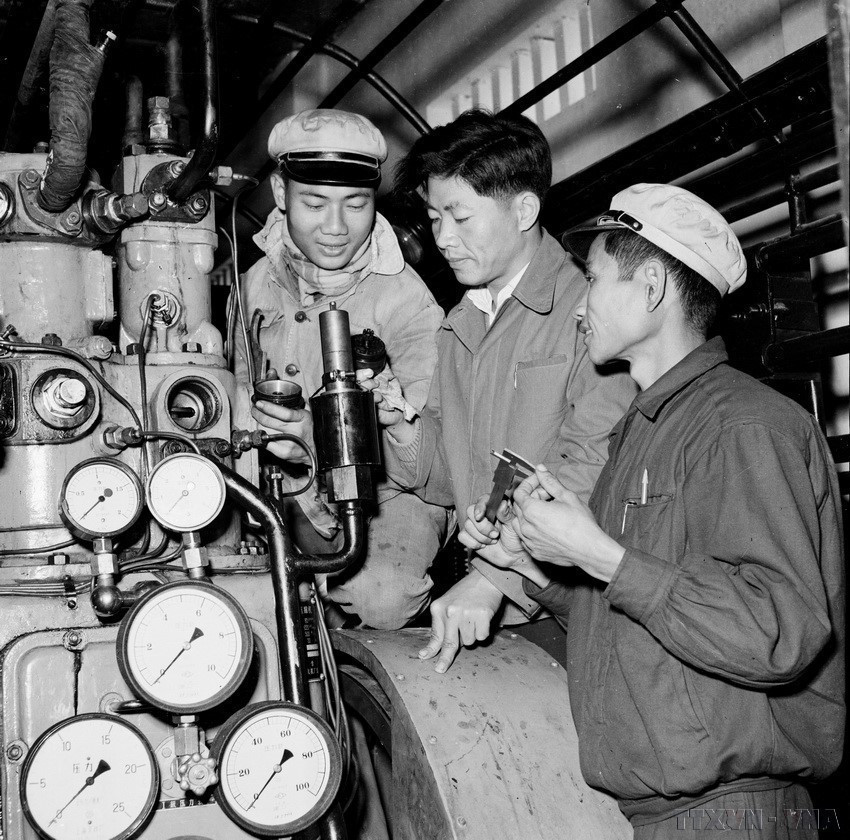 A Chinese expert (center) guides Vietnamese workers in dismantling and repairing an automatic steam release valve at the K65 pressing plant (September 1960). (Photo: VNA)