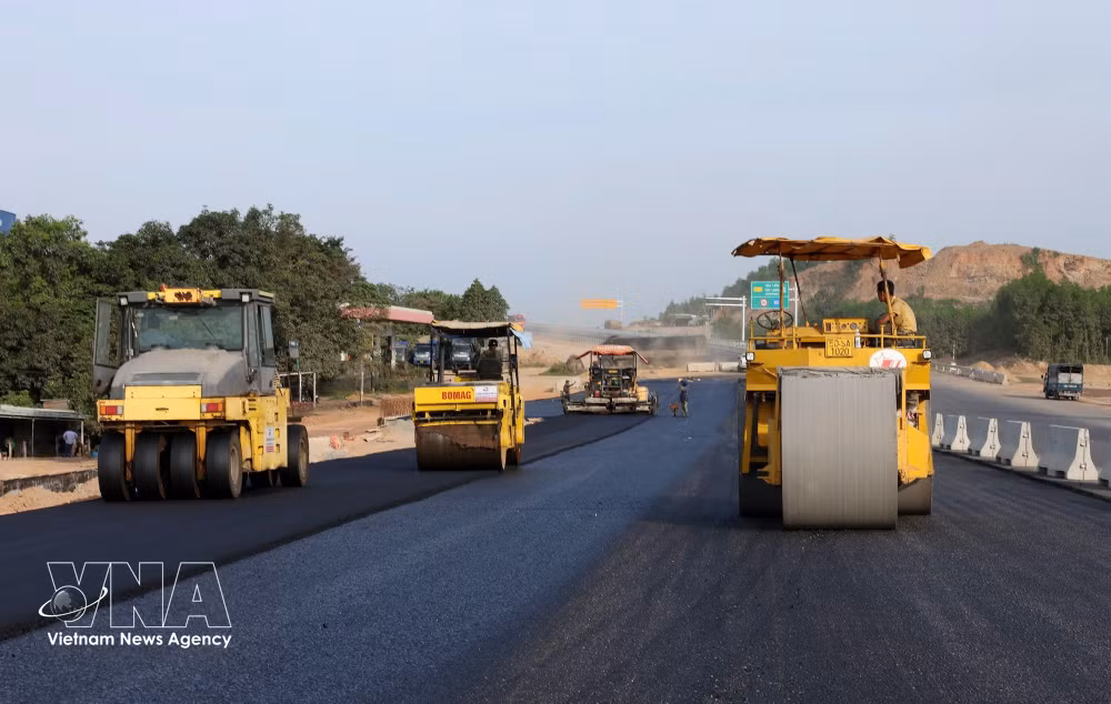 Contractors mobilise machinery and workforce to lay asphalt concrete on an expressway project. (Photo: Vietnamplus)