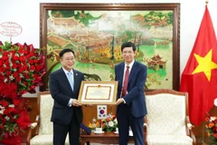 Deputy Minister of Culture, Sports and Tourism Ho An Phong presents a certificate of merit to Ly Xuong Can for his contributions to promoting tourism cooperation between the two countries. (Photo: VNA)