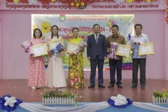 Vietnamese Ambassador to Laos Nguyen Minh Tam presents certificates of merit to the Vietnamese community in Vientiane and leaders of the Nguyen Du Lao-Vietnamese bilingual school for their contributions to preserving Vietnamese culture. (Photo: VNA)