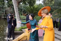 Queen Mathilde joins First Lady Nguyen Thi Minh Nguyet in feeding fish in Uncle Ho’s pond at the President Ho Chi Minh Memorial Site on April 1. (Photo: VNA)
