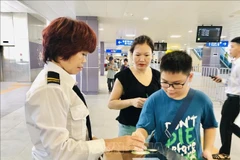 Hanoi Metro staff assist passengers at the ticket gate. (Photo: VNA)
