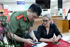 A police officer instructs a foreigner how to register for a level-2 electronic identification account. (Photo: VNA)