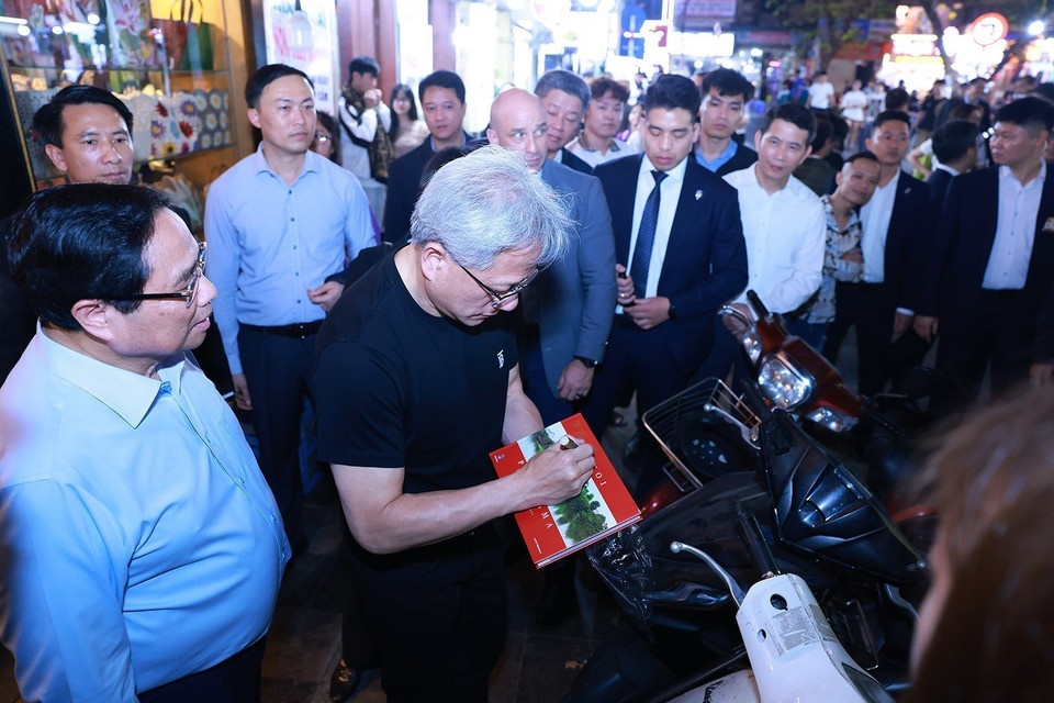 Prime Minister Pham Minh Chinh and President and CEO of NVIDIA Jensen Huang sign books for the locals. Photo: Duong Giang - VNA.