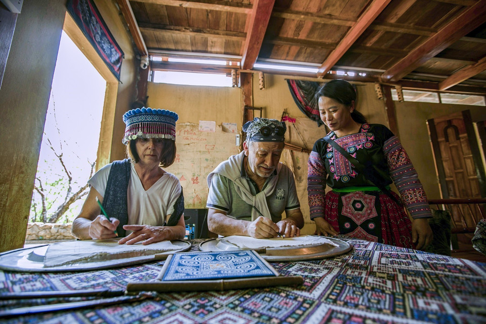French tourists try beeswax painting on Mong ethnic brocade at the Y Mua homestay in Hang Kia commune. (Photo: VNA)