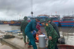 Border guard officers at Ky Ha Port Border Gate are assisting residents in securing their boats. (Photo: VNA)