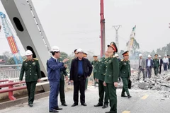 Minister of Transport Tran Hong Minh (central, in black) inspects the work at the construction site of the new Phong Chau bridge in the northern province of Phu Tho. (Photo: VNA)