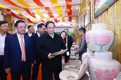 Prime Minister Pham Minh Chinh visits a booth displaying handicraft and fine arts products. (Photo: VNA)