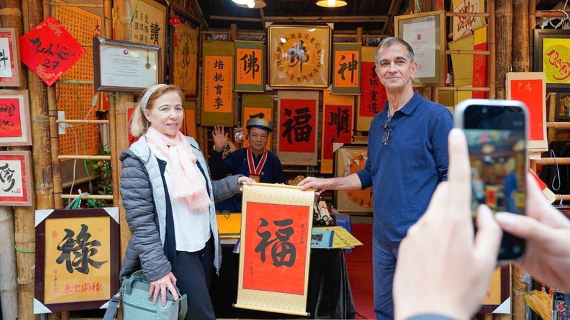 International visitors experience the traditional new year calligraphy activity (Photo: VNA)