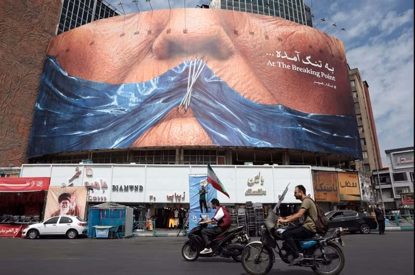 Motorists ride past an anti-US billboard referring to President Donald Trump and the Strait of Hormuz at Valiasr Square in Tehran on May 2, 2026. ( Photo: AFP) 
