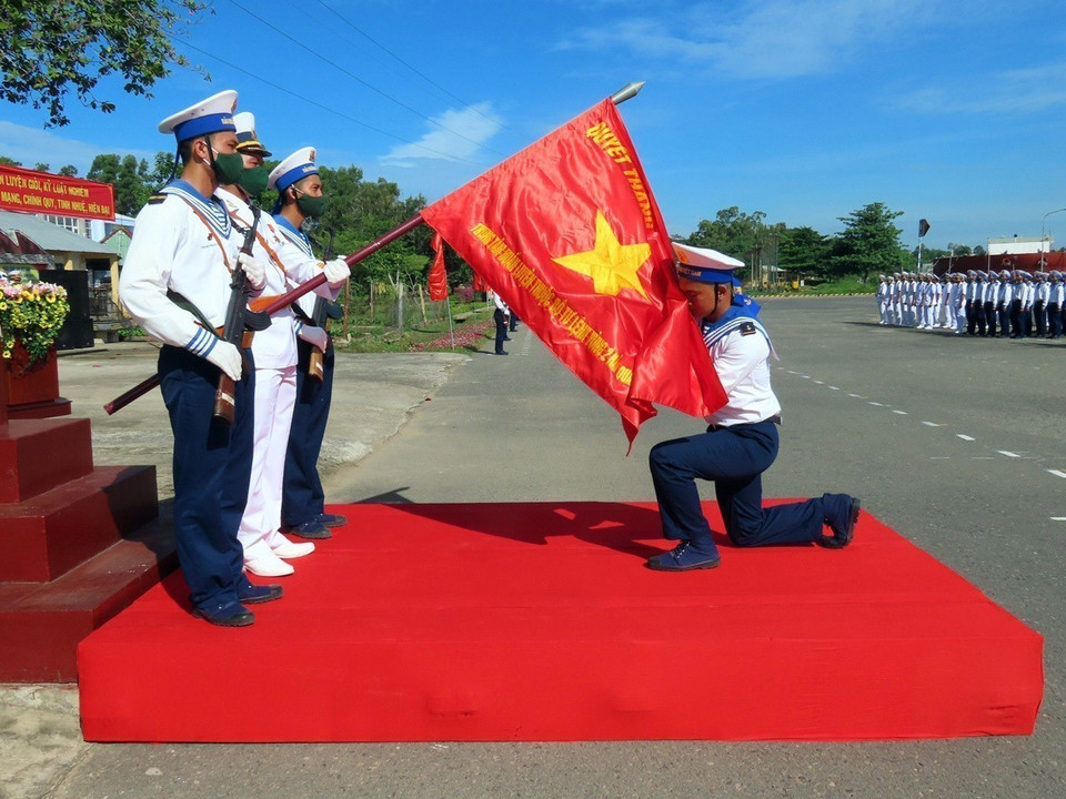 Newly-enlisted soldiers perform the tradition of kissing the National Flag during the oath-taking ceremony before departing for their assigned duties at units within Naval Zone 2. (Photo: VNA)