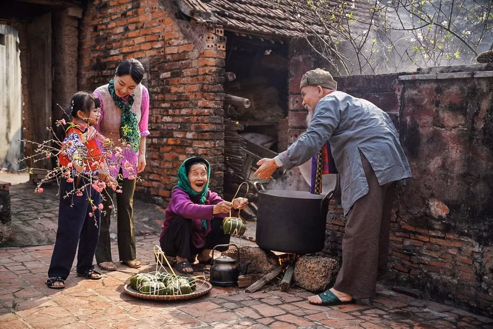 Generations of a family gather around the pot of banh chung (traditional square sticky rice cake). (Photo: Khanh Hoa - VNA)