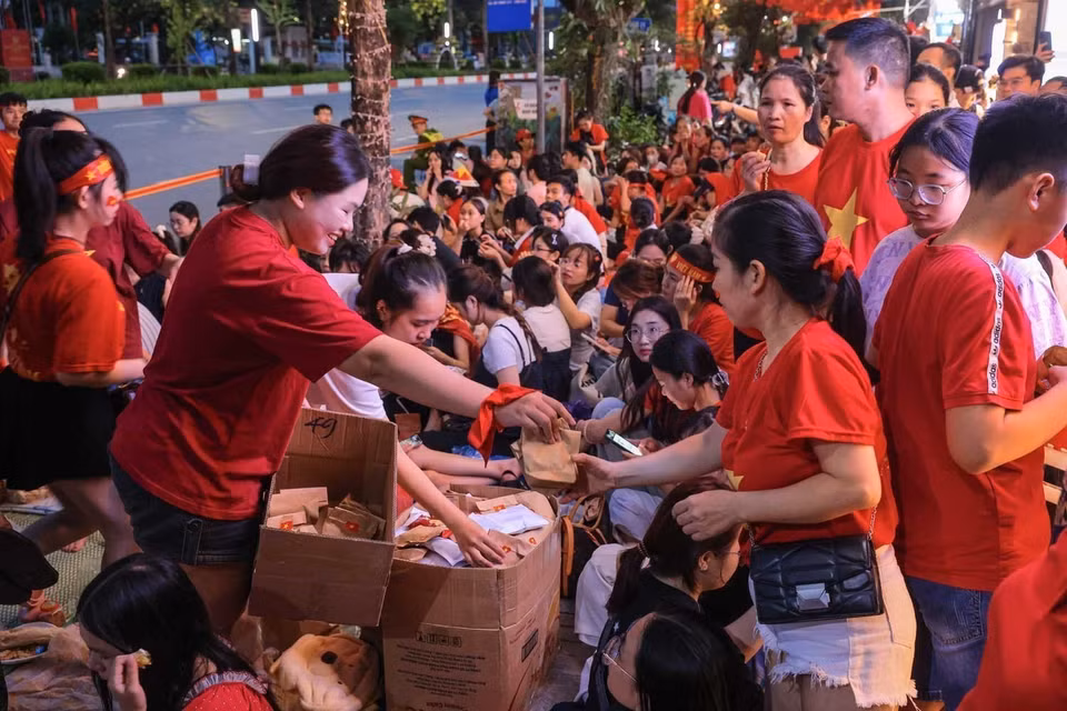 Residents voluntarily share food with one another while staying up on Van Cao Street on the night of August 29 to watch the full-dress parade rehearsal. Photo: Hoang Hieu - VNA