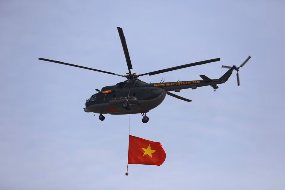 A helicopter proudly trails the national flag across the sky. (Photo: VNA)