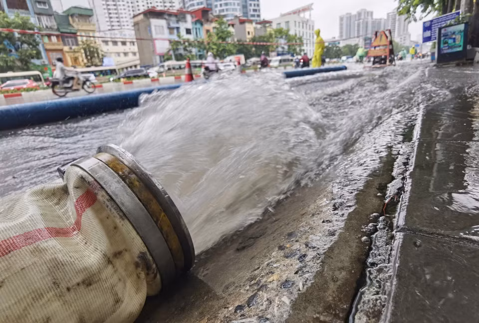 Workers on duty draining floodwater on Minh Khai street. (Photo: VNA)