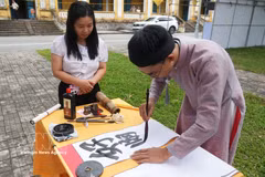 A visitor watches a calligraphy demonstration at the first Vietnam Calligraphy Festival 2026. (Photo: VNA)