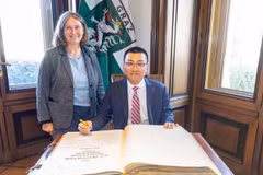 Elke Kahr, former Deputy Chairwoman of the Communist Party of Austria Central Committee and Mayor of Graz, and Vietnamese Ambassador to Austria Vu Le Thai Hoang (sitting) sign the city of Graz’s guest book. (Photo courtesy by the Vietnamese Embassy in Austria)