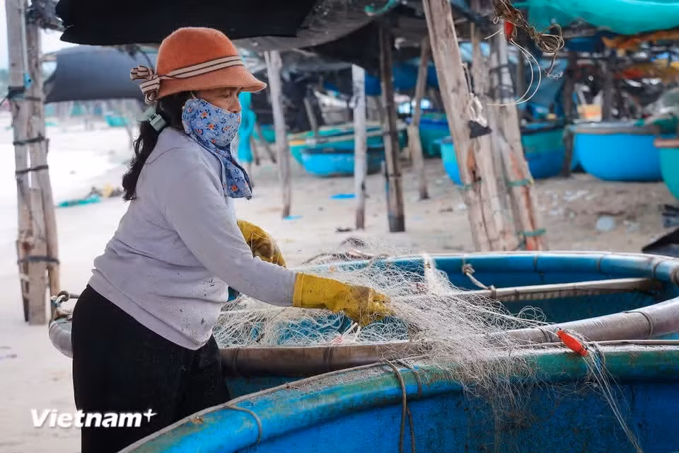 After each trip, fishermen busily mend their nets in preparation for their next journey to sea. (Photo: VietnamPlus)