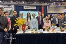 Ambassador Pham Vinh Quang (seventh from left) poses for a photo with staff of the Vietnamese Embassy in Canada at the Vietnam booth at the exhibition. (Photo: VNA) 
