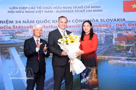 Ha Thanh (right), Chairwoman of the Ho Chi Minh City Union of Friendship Organsations, and Bui Quang Hai (left), Chairman of the Ho Chi Minh City Vietnam–Slovakia Friendship Association, present flowers to Marian Veres, Chargé d’Affaires ad interim of the Embassy of Slovakia in Vietnam at the ceremony on August 27. (Photo: VNA) 