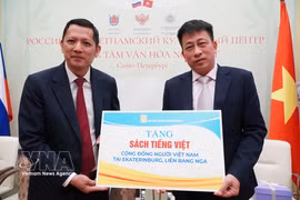 Editor-in-Chief of the Vietnam Education Publishing House Pham Vinh Thai (right) symbolically presents books to the Vietnamese community in Russia. (Photo: VNA) 