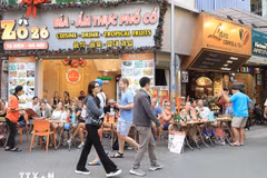 Foreign tourists savour local foods on Ta Hien street in Hanoi. (Photo: VNA)