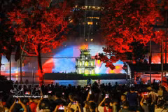 Large crowds gather around Hoan Kiem Lake to watch a 3D mapping light show projected onto Turtle Tower, accompanied by a water-screen display. (Photo: VNA)