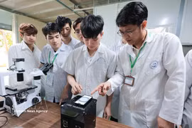 A lecturer of the Vietnam National University of Agriculture instructs students in how to use a piece of equipment integrated with AI and IoT to conduct research. (Photo: VNA)