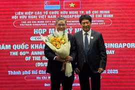 Chairman of the Vietnam–Singapore Friendship Association of Ho Chi Minh City Lam Dung Tien presents flowers to Singapore Consul General in HCM City Pang Te Cheng at the gathering. (Photo: sggp.org.vn)