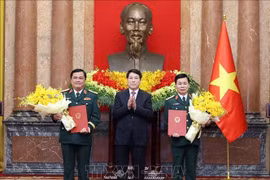 State President Luong Cuong (middle) presents congratulatory flowers to the two promoted officers (Photo: VNA)
