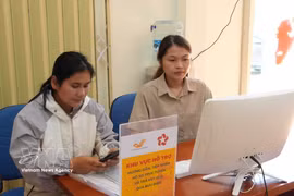 A member of the community-based digital technology team in Tu Mo Rong commune, Quang Ngai province, guides a resident in how to submit applications for administrative procedures online. (Photo: VNA)