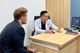 D.F (left), a US patient, at a follow-up examination with Do Lenh Hung, head of the department of urethral reconstructive surgery. (Photo: VNA)