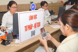 A citizen scans a QR code to look up procedures and processes related to judicial and civil registration matters. (Photo: VNA)