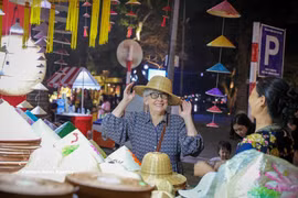 A foreigner is drawn to Vietnam's traditional products at the Hanoi Tourism Gift Festival 2025. (Photo: VNA)