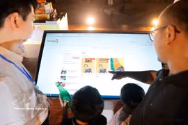 Visitors experience an e-book app (Photo: VNA)
