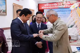 Phonesy Bounmixay (right), Lao Consul General in Ho Chi Minh City, performs the traditional baci string-tying ceremony to offer New Year blessings to a member of the Ho Chi Minh City delegation on April 10, 2026. (Photo: VNA)