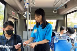 A passenger (left) buys a ticket on a bus in Hanoi. (Photo: VNA)
