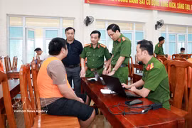 A suspect from the transnational online fraud ring is investigated (Photo: VNA)