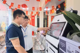 A civil servant at the Chi Lang commune Public Service Centre in Lang Son province guides a resident in how to use an AI-supported public service kiosk. (Photo: VNA)