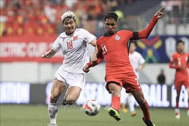 Thanh Binh (white's dribbling is fiercely blocked by a Singaporean defender at the first leg of the ASEAN Cup semifinal on December 26. (Photo: VNA)