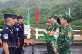Commanders of the Vietnamese and Chinese patrol teams exchange flowers at the demarcation line on the Vietnam-China border friendship bridge (Photo: VNA) 
