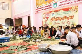 Teachers and students at the Nguyen Du Lao-Vietnamese bilingual language school in Vientiane make "chung" cakes. (Photo: VNA)