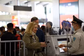 An aviation security official checks passenger information before security screening. (Photo: VNA)