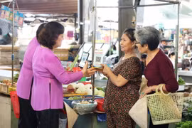 Vendors guide customers in making cashless payments in Ho Chi Minh City. (Photo: phunuonline.com.vn)