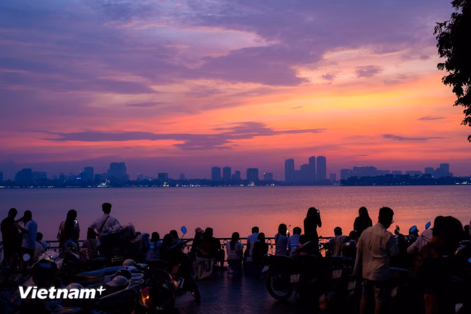Sunset over West Lake paints the water with surreal streaks of orange, pink and purple. (Photo: VietnamPlus)