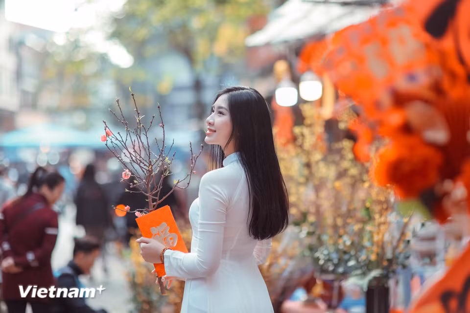Along central streets, Hanoians in graceful ao dai (traditional long dress) stroll leisurely for photos, creating a scene quintessential to Tet in the capital. (Photo: VietnamPlus)